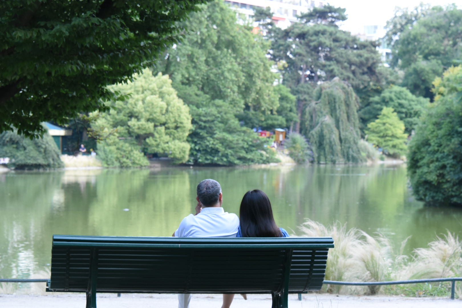 Un couple assis sur un banc face à un lac