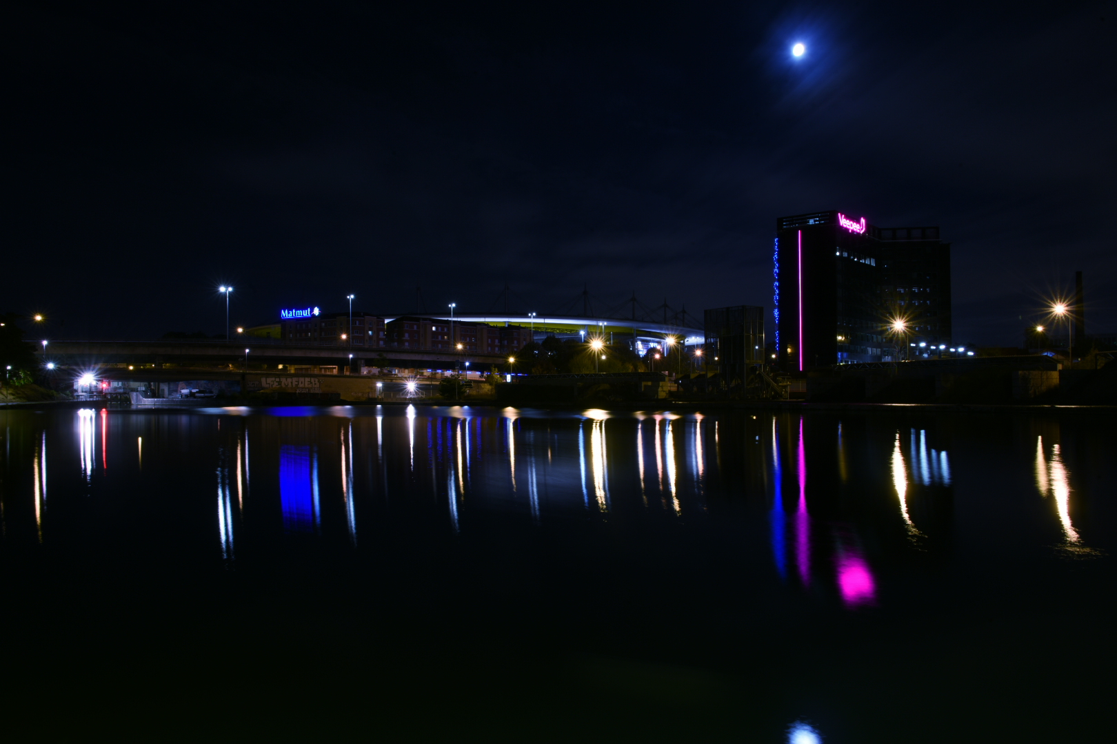 Le canal reflète les lumières de Saint-Denis, avec le stade de France au fond